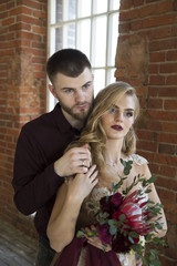 bride and groom pose near window and vintage brick wall