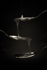 Honey pouring from spoon against a dark background