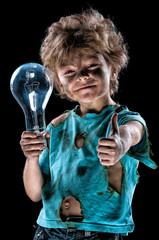 Boy has a electric shock. Portrait of funny little electrician with light bulb doing a thumb...