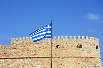 Part of Koules castle with a Greek flag in the foreground, Heraklion.