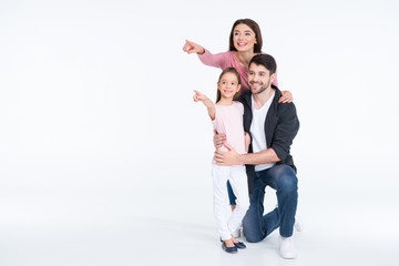 Fototapeta premium Happy young family standing together and pointing with fingers on white