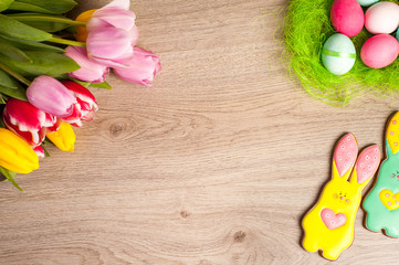 Easter composition of the branches,Easter bunny, cakes, tulips colored eggs cooked for the holiday on the wooden background