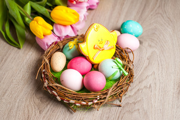 Obraz na płótnie Canvas Easter composition of the branches,Easter bunny, cakes, tulips colored eggs cooked for the holiday on the wooden background