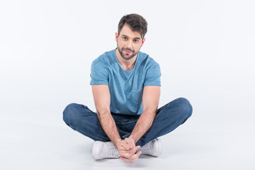 smiling man sitting on floor on white