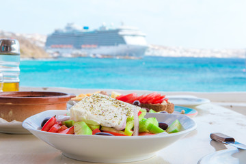 Traditional lunch with delicious fresh greek salad and brusketa served for lunch at outdoor cafe with view on the sea