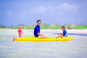 Fototapeta na wymiar Young father and two little kids kayaking at the sea