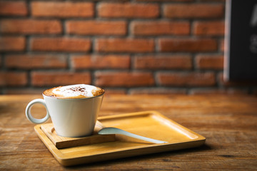 Cup of hot latte art coffee on wooden table. A stylish modern café with wooden tables and a brick wall.