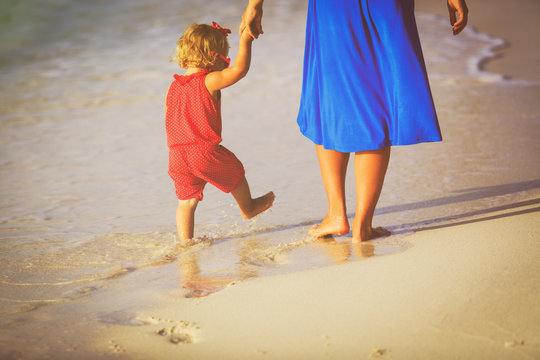 Mother And Little Daughter Walking On Beach