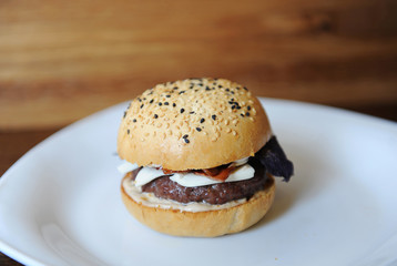 Burger on a white plate. Wooden background