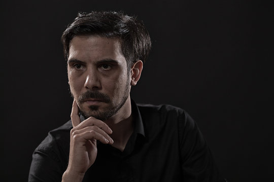 Portrait of pensive adult man on black background.