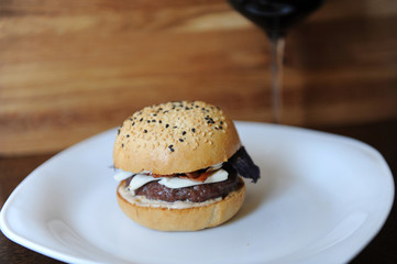 Burger and a glass of red wine on a wooden background. Free space for design