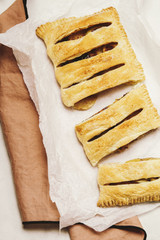 Sliced fresh-baked crunchy homemade apple strudel on a baking paper. Top view. Selective focus. Toned image