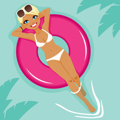 Beautiful young blonde woman sunbathing resting on big pink inflatable float on water