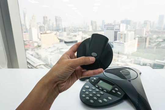 woman hold mobile speaker of conference phone in office