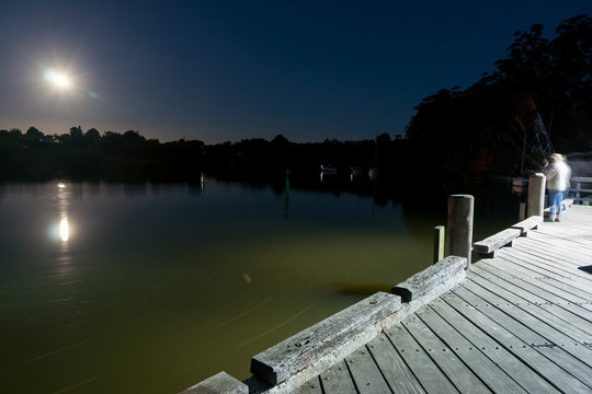 Couple blurred in motion of long exposure fishing from Kerikeri wharf at night.