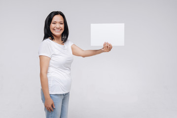 Cheerful elegant woman showing a white piece of paper