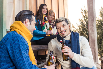 smiling men talking while drinking beer with women looking at them