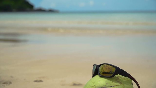 Green coconut on the sand of a tropical beach in sunglasses. Coconut funny wearing sunglasses on the beach. Fresh coconut from palm on a sandy beach. Philippines , El Nido. 4K video Travel concept.