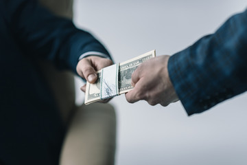 partial view of businessman taking money from colleague