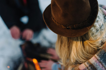 stylishly dressed young couple, sitting near the fire in the winter forest