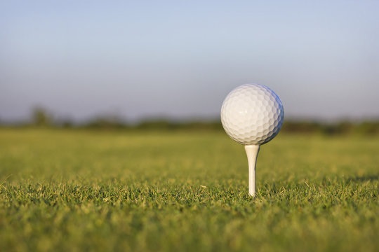 Closeup image of a golf ball on a tee on the grass.