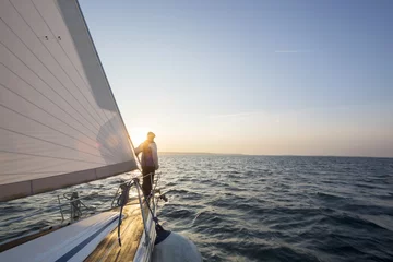 Rolgordijnen Man Standing On Front Of Luxury Yacht In Sea © Tyler Olson