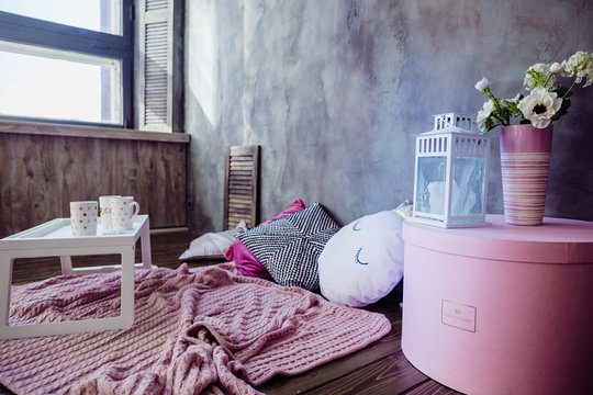Cosy corner made of pink decor, soft pillows and woolen blanket on the floor