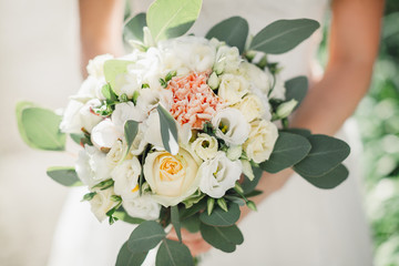 Bride holds gorgeous white bouquet with pastel green leaves