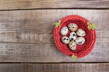 Red nest with quail eggs and young tree leaves. Easter 
Easter composition on a wooden background.
