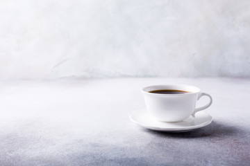 White cup of coffee with amaretti cookies on light gray background with copy space.