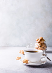 White cup of coffee with amaretti cookies on light gray background with copy space.