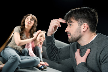 Aggressive man gesturing while scared woman closing ears of little daughter, family problems concept