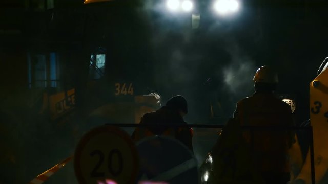 Workers and vehicles during the asphalting of the highway by night
