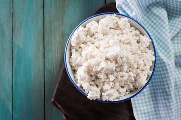 Homemade cottage cheese in a bowl on old wooden table.