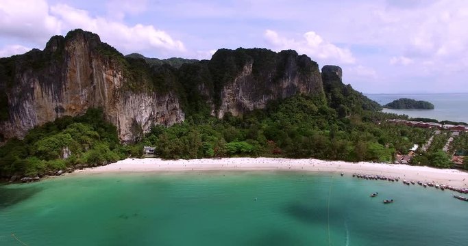 Aerial view flying over Thai island towards beautiful green mountains and white sandy beach. Krabi island, Thailand