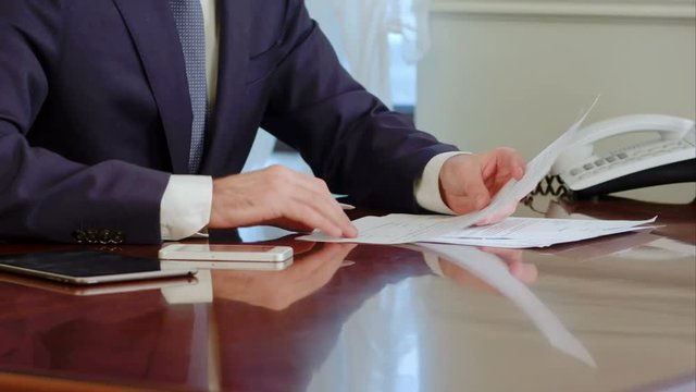 Man hand signs a paper document with ballpoint pen. Signature is fake.