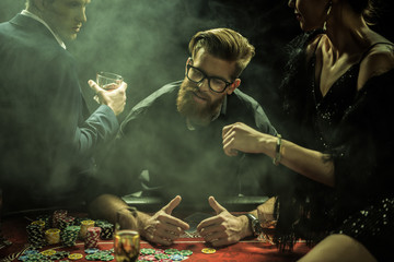 portrait of man playing poker while friends sitting on table in casino