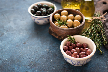 bowls with different kind of olives green olives, black olives, kalamata olives on table