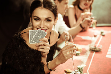 portrait of smiling woman with drink and cards playing poker