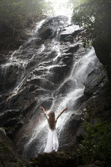 woman rising hands posing under waterfall Than Sadet,koh Phangan island,Thailand