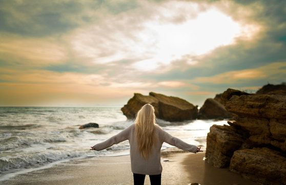 Woman In Sweater On Winter Beach At Sunset.