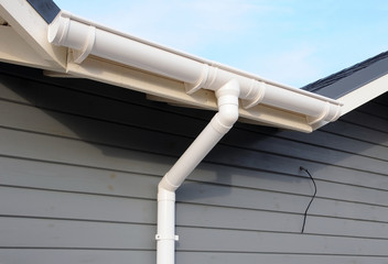New rain gutter on a home against blue sky. New roof.