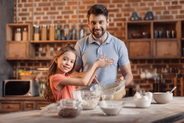 'portrait of father and daughter making cookies in kitchen