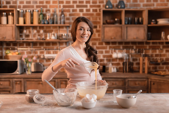 'portrait of smiling woman mixing ingredients for cake