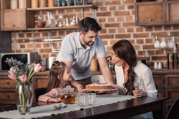 'portrait of father and daughter presenting mother cake for mother's day holiday in kitchen
