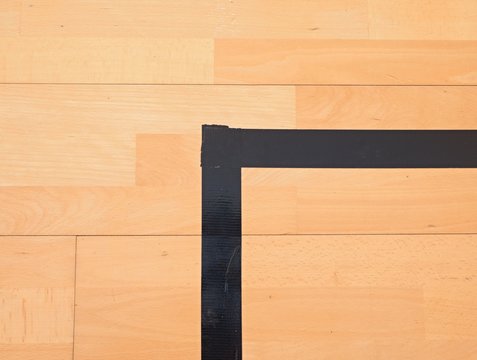 Black corner. Worn out wooden floor of sports hall