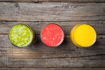 Glasses of fresh juice on an old wooden background