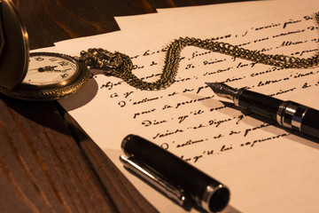 Naklejka premium On the table lie a pocket watch and a fountain pen