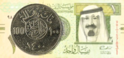 100 saudi riyal coin against 1 saudi riyal bank note obverse