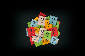 Pile of colorful paper notes with question marks on blackboard